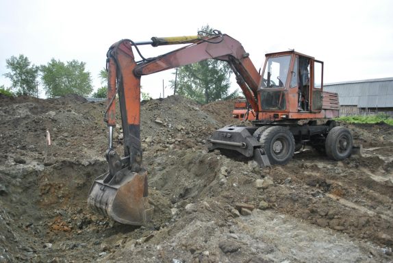 Bagger arbeitet im Erdboden und hebt Erde auf einer Baustelle.