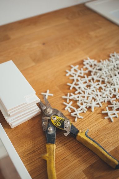 Zwei Zangen und weiße Abstandshalter auf einem Holztisch.