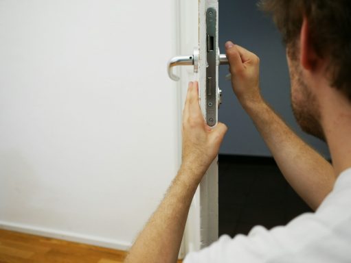 Eine Person öffnet eine Tür mit einem Schlüssel. Hintergrund unscharf.